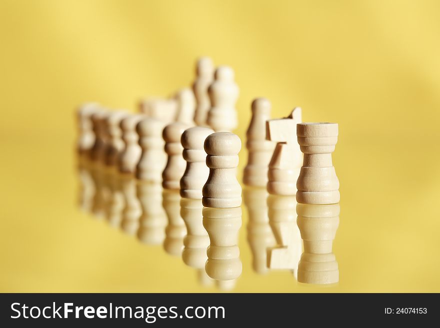 Chessman set in a row on yellow background with reflection. Chessman set in a row on yellow background with reflection