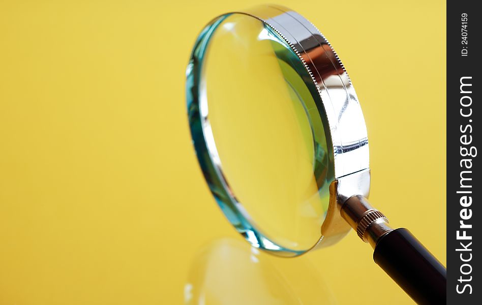 Closeup of magnifying glass on yellow background