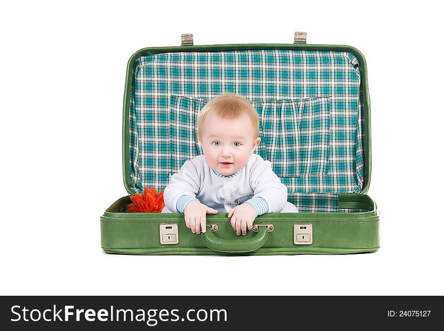 Baby sitting in an old green suitcase in anticipation of traveling on a white background