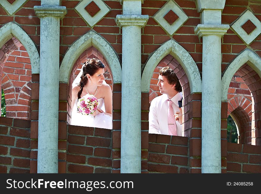 Happy bride and groom in windows of brick wall