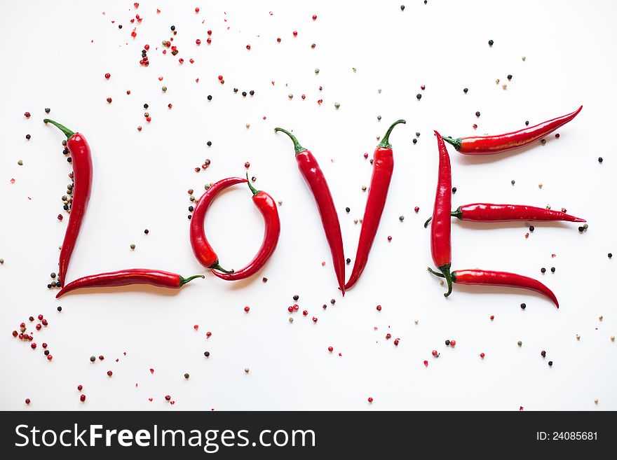 Red chili peppers shapes the word Love, surrounded with peppercorns on a white background. Red chili peppers shapes the word Love, surrounded with peppercorns on a white background