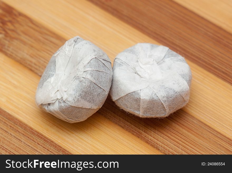 Two bricks of pu-erh tea wrapped on paper on bamboo background