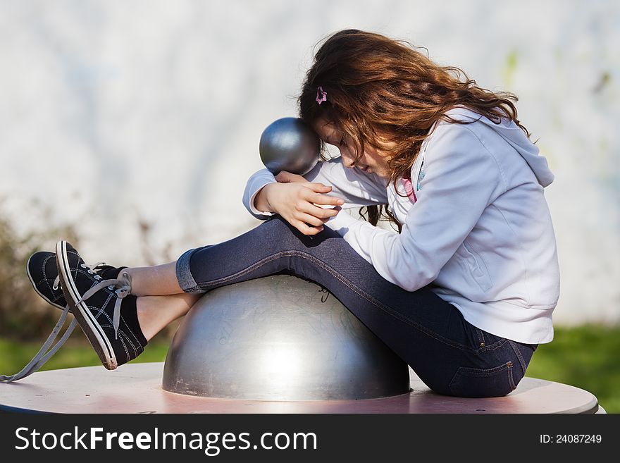Young girl sits on a playground equipment and dreams. Young girl sits on a playground equipment and dreams