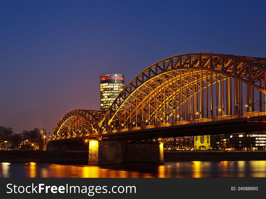 Night picture at the blue hour from Hohenzollern railway bridge in Cologne, Germany, with the rhine in the foreground and the LVR tower in the background. Night picture at the blue hour from Hohenzollern railway bridge in Cologne, Germany, with the rhine in the foreground and the LVR tower in the background