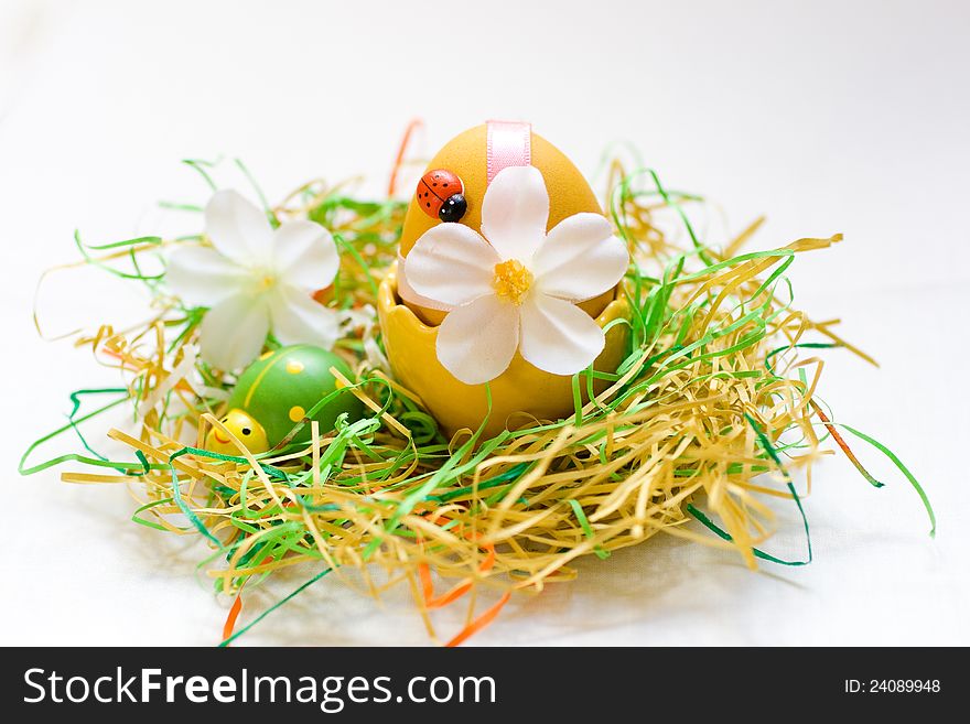 Painted yellow easter egg with a ladybug in a nest with white flower. Painted yellow easter egg with a ladybug in a nest with white flower.