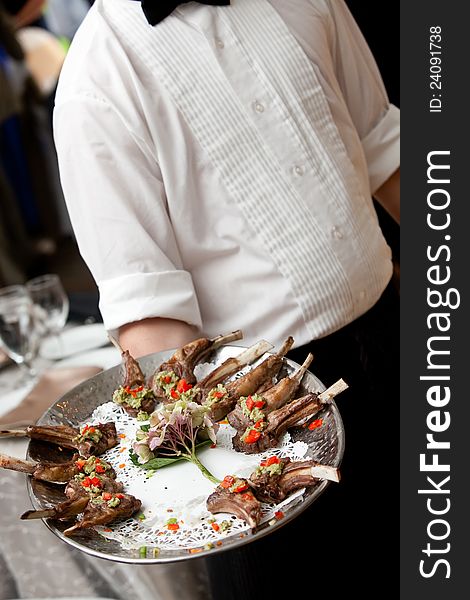 A waiter serving appetizers on a platter during a catered event. A waiter serving appetizers on a platter during a catered event