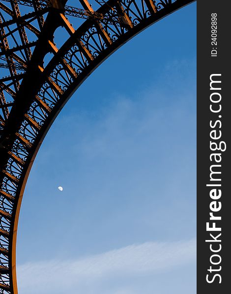 A detail of the famous Eiffel Tower in Paris with the moon at the sky. A detail of the famous Eiffel Tower in Paris with the moon at the sky