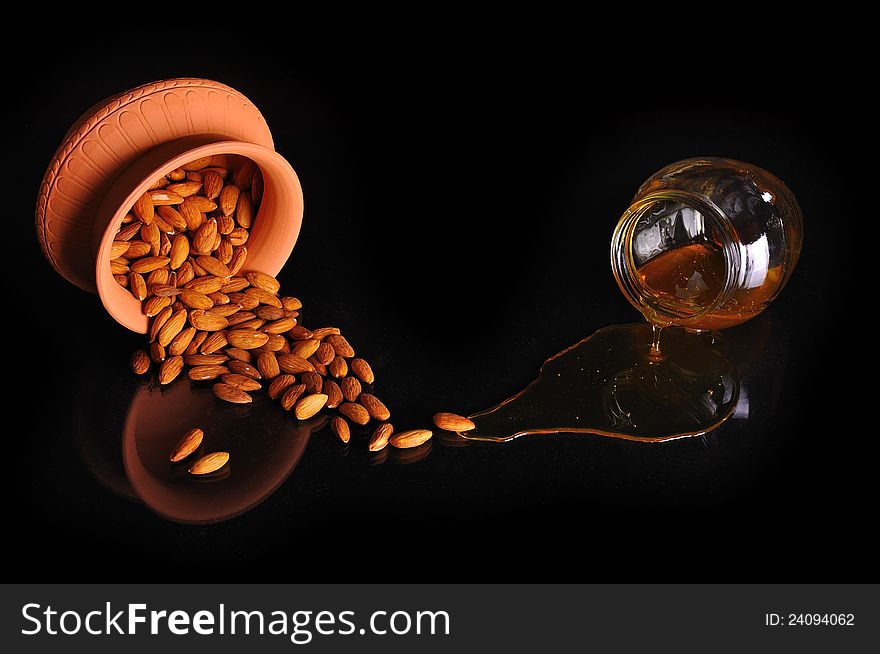 Bowl with almonds, honey jar, on a black surface. Bowl with almonds, honey jar, on a black surface