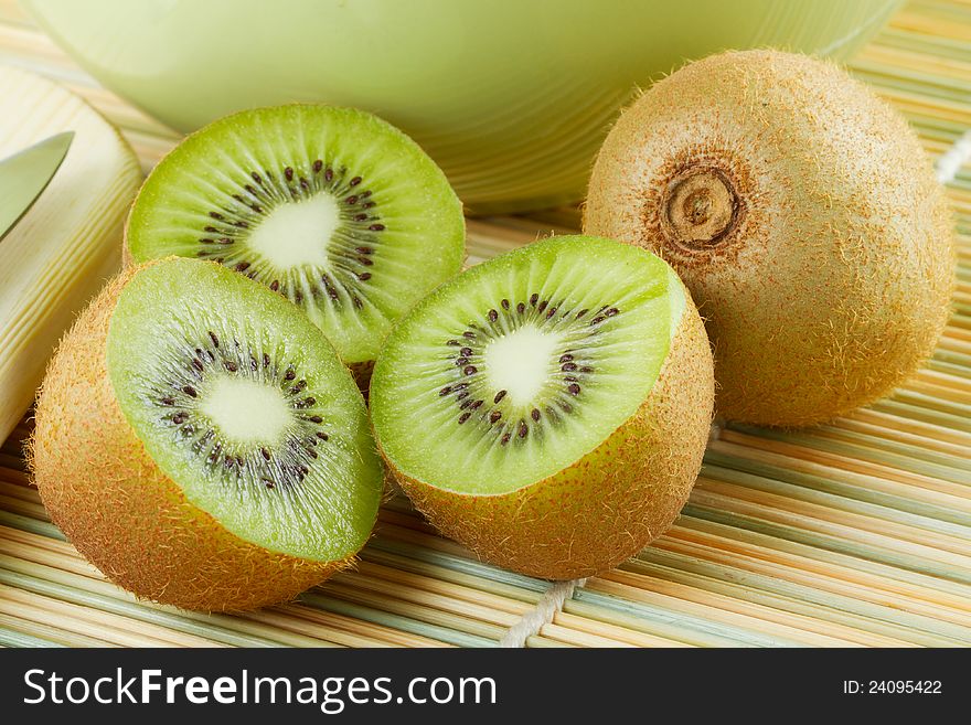 Kiwi sliced and whole fruits, green bowl on table