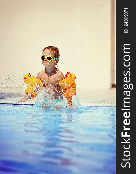 Outdoors in the pool the child swims. Outdoors in the pool the child swims