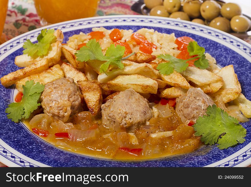 Close view of a meal of meat balls with rice and potatoes.