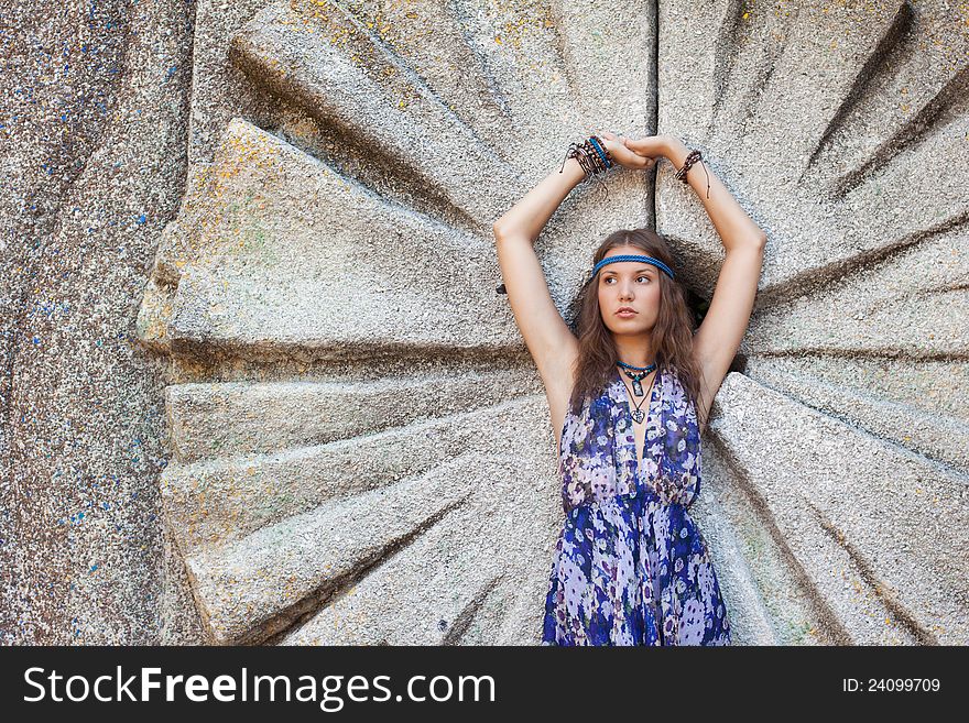 Young woman in a sundress at the stone wall