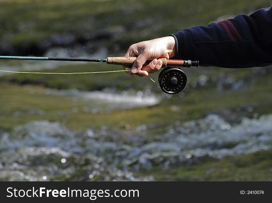 A man in river fishes trouts with rod. A man in river fishes trouts with rod