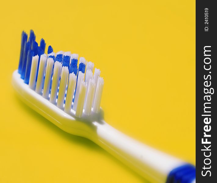 Bristle of a toothbrush against yellow background.