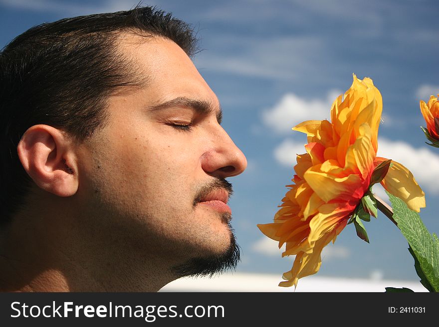 Young man with a flower on the blue sky background. Young man with a flower on the blue sky background