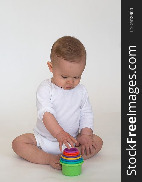 Image of an adorable baby playing with colorful stacking cups. Image of an adorable baby playing with colorful stacking cups