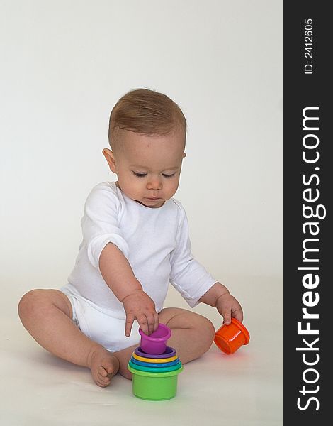 Image of an adorable baby playing with colorful stacking cups. Image of an adorable baby playing with colorful stacking cups