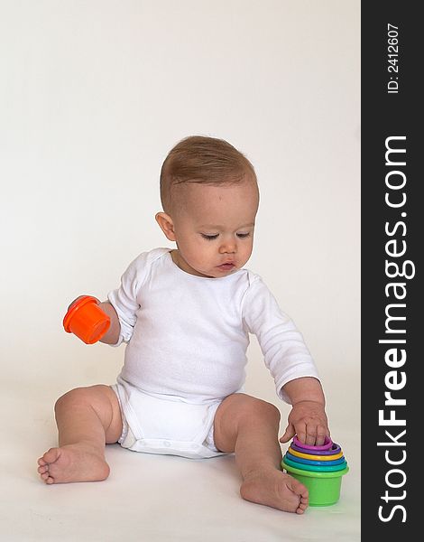 Image of an adorable baby playing with colorful stacking cups. Image of an adorable baby playing with colorful stacking cups