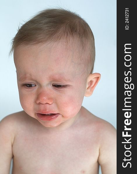 Image of crying baby sitting in front of a white background