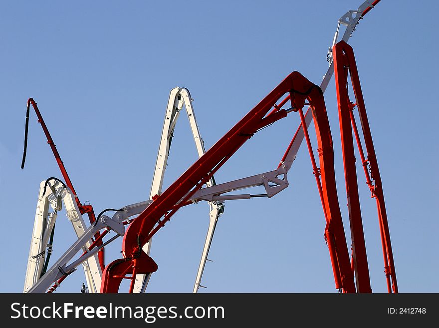 Fragments of concrete pumps arms on a blue sky. Fragments of concrete pumps arms on a blue sky