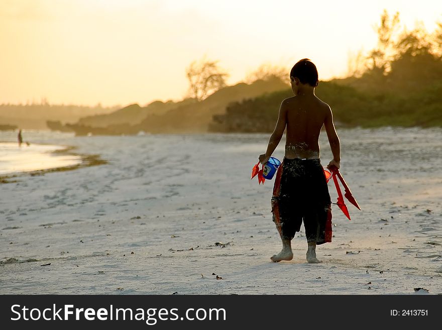 Young boy carrying his toys to the beach, Indian Ocean, Kenya. Young boy carrying his toys to the beach, Indian Ocean, Kenya