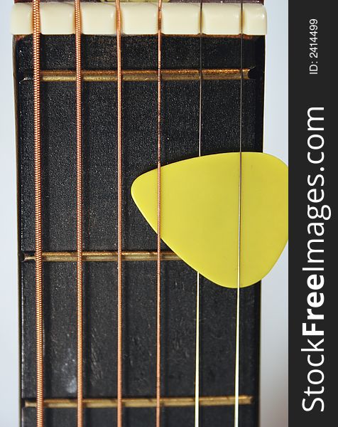 An image of a Acoustic Guitar Neck with Yellow Pick