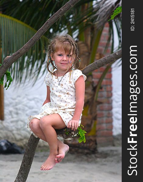 Cute little girl posing while sitting on the tree. Cute little girl posing while sitting on the tree