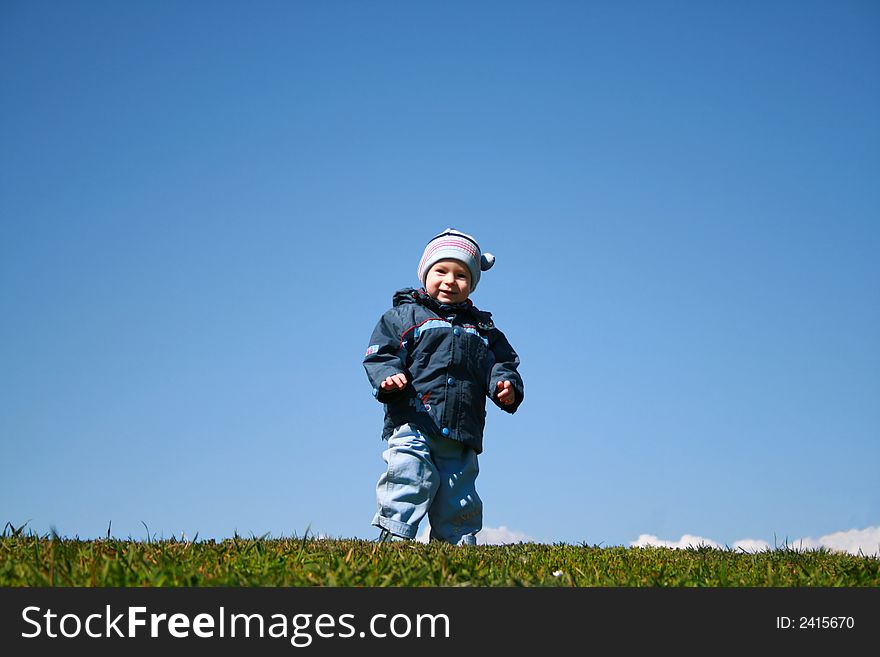 The child on a glade on a background of the sky. The child on a glade on a background of the sky