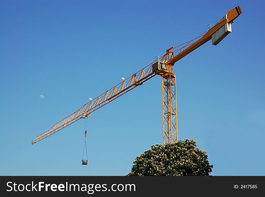 Construction cranes, blue sky and full moon