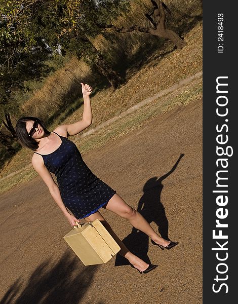 Brunette waiting roadside for a lift standing roadside with thumb in air. Brunette waiting roadside for a lift standing roadside with thumb in air