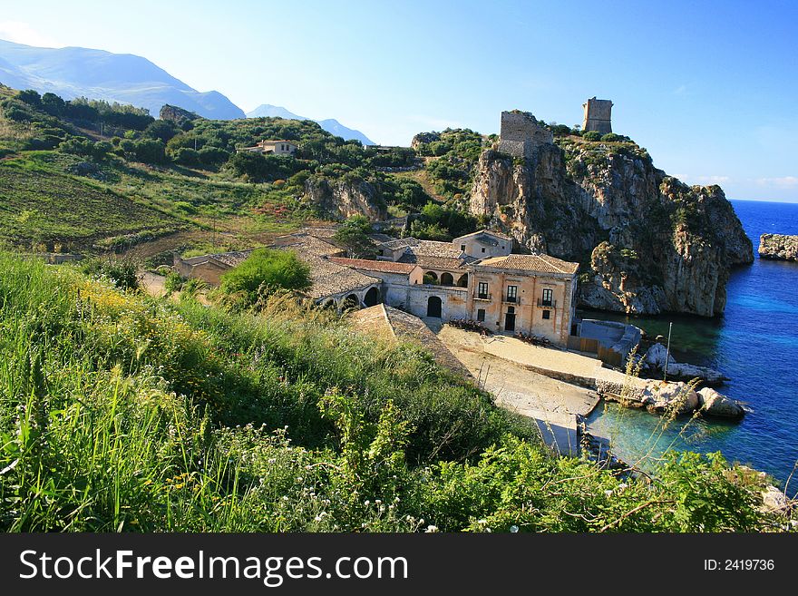 Blue Mediterranean Landscape. Coast, Rocks and sea.Wien on the ancient tuna fishing construction and bay. Sicily Summer Italy. Blue Mediterranean Landscape. Coast, Rocks and sea.Wien on the ancient tuna fishing construction and bay. Sicily Summer Italy