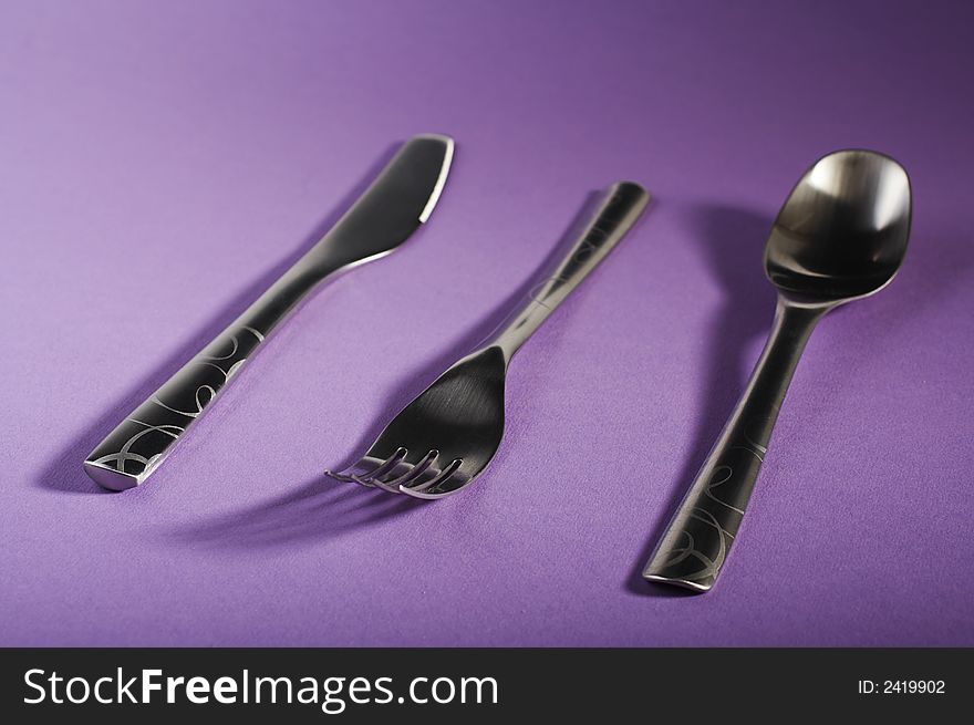 Modern spoon, fork and knife on purple table. Modern spoon, fork and knife on purple table.