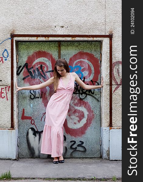 Beautiful young girl standing at the door with graffiti