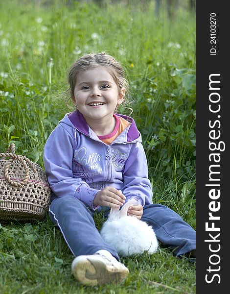 Little girl smiling with little white rabbit on the grass. Little girl smiling with little white rabbit on the grass
