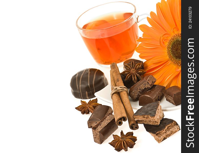 Cup of tea with a lemon, cinnamon, anise, round chocolate biscuits and gerbera on a white background. Cup of tea with a lemon, cinnamon, anise, round chocolate biscuits and gerbera on a white background