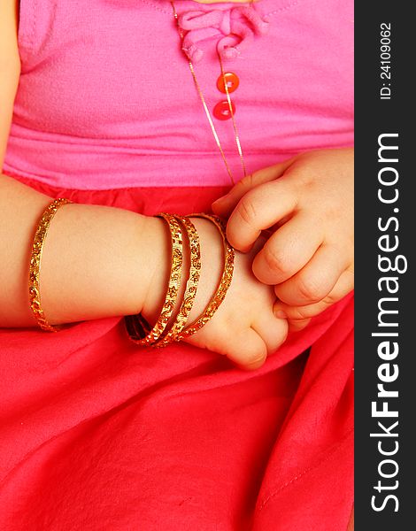 Baby hands, with golden bracelets, towards dark red