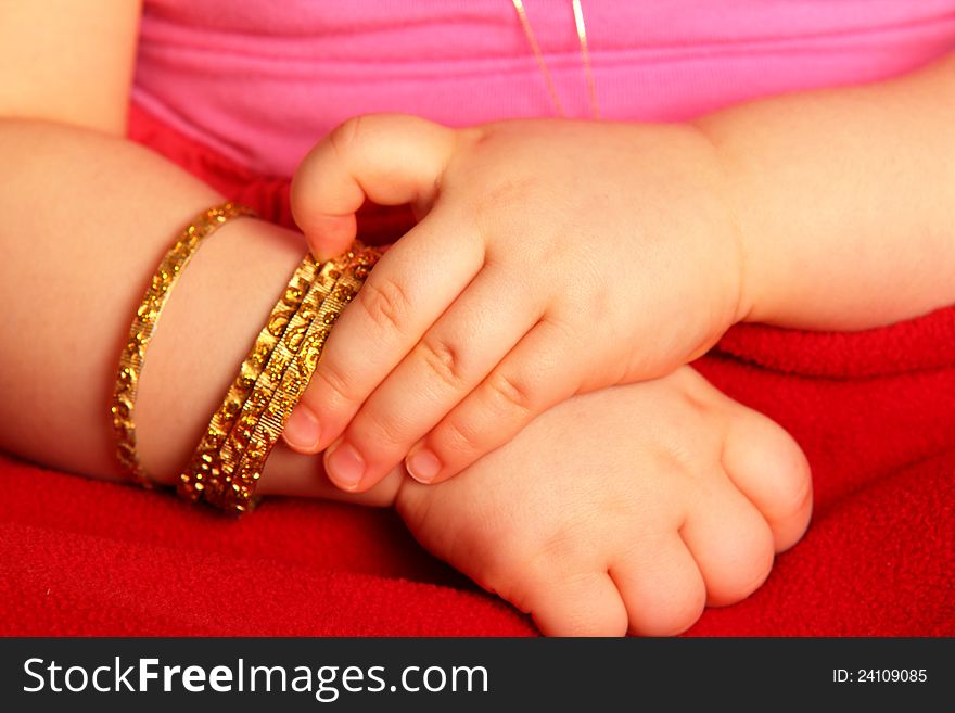 Baby hands, with golden bracelets,  towards dark red