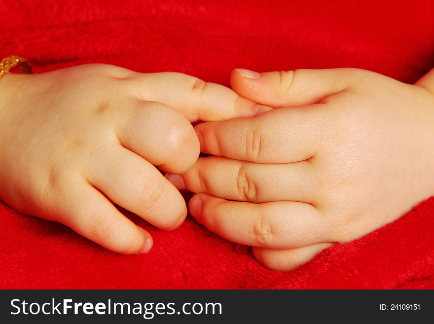 Baby holding hands,  towards dark red