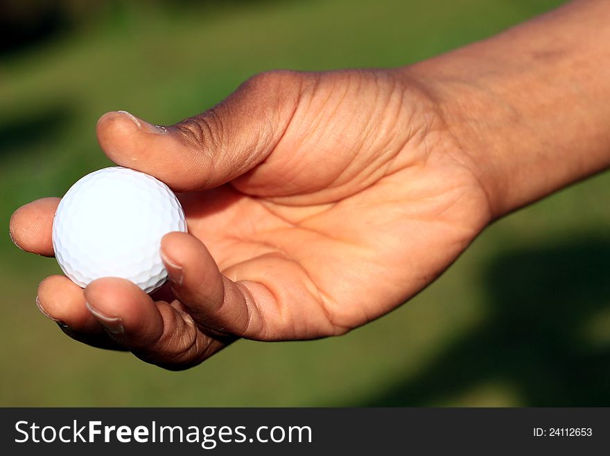 Image of a Golf ball and hand on a green background