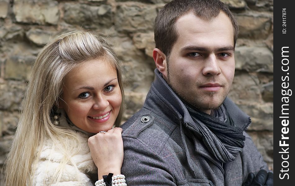 Young Woman Smiling From Behind Her Boyfriend Near Old Brick Wall