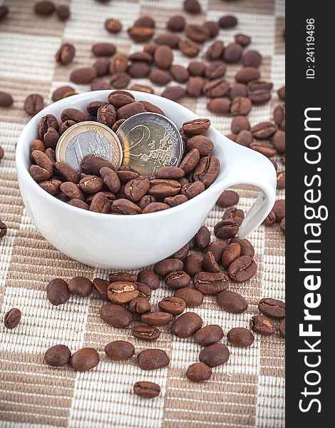 White ceramic cup with coffee seed and euro coins