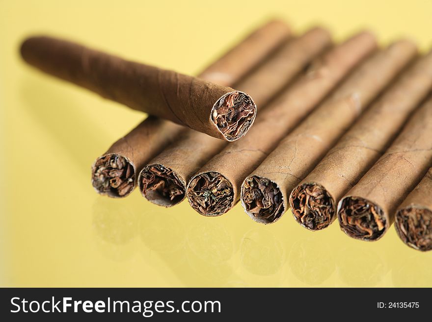 Closeup of few cigars in a row on yellow background. Closeup of few cigars in a row on yellow background