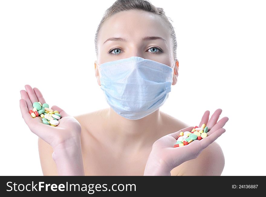 Beautiful nurse in a mask with a variety of pills on the palms. Beautiful nurse in a mask with a variety of pills on the palms