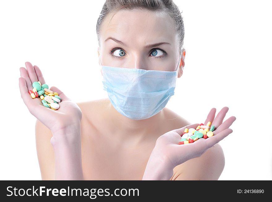 Beautiful funny nurse in a mask with a variety of pills on the palms. Beautiful funny nurse in a mask with a variety of pills on the palms