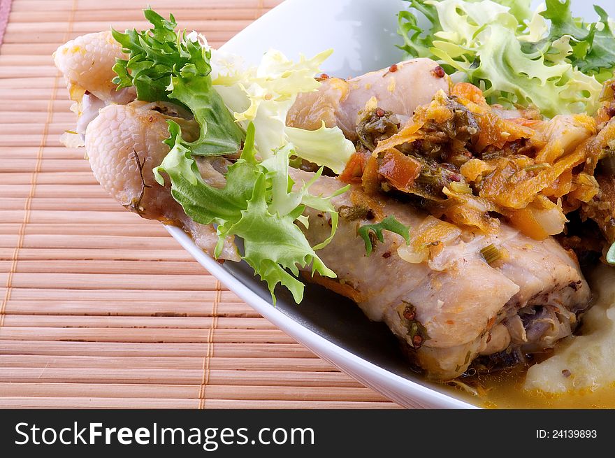 Roasted chicken legs with vegetables saute and greens close up on wooden background