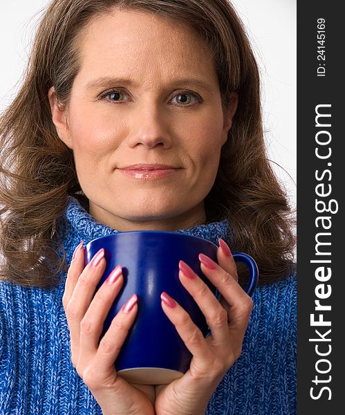 Closeup of a beautiful caucasian woman in her 40s holding a nice blue cup of warm beverage. Closeup of a beautiful caucasian woman in her 40s holding a nice blue cup of warm beverage