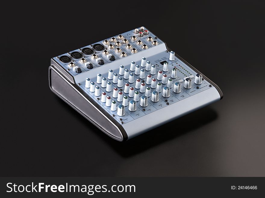 A sliver blue audio mixing board isolated on a lightly textured, soft black background.