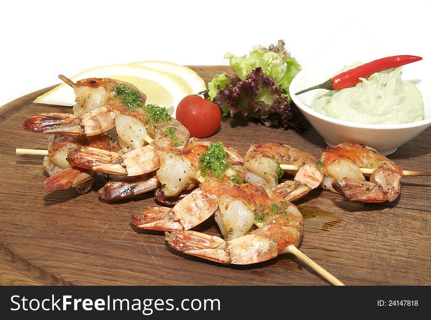 Skewers of shrimp with herbs on a wooden plate