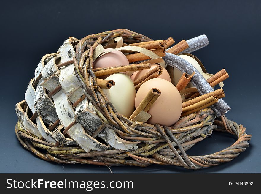 Basket of organic free-range eggs with candy and cinnamon sticks. Basket of organic free-range eggs with candy and cinnamon sticks