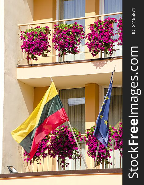 Lithuania and European Union flag hanging under building balcony with flowers.